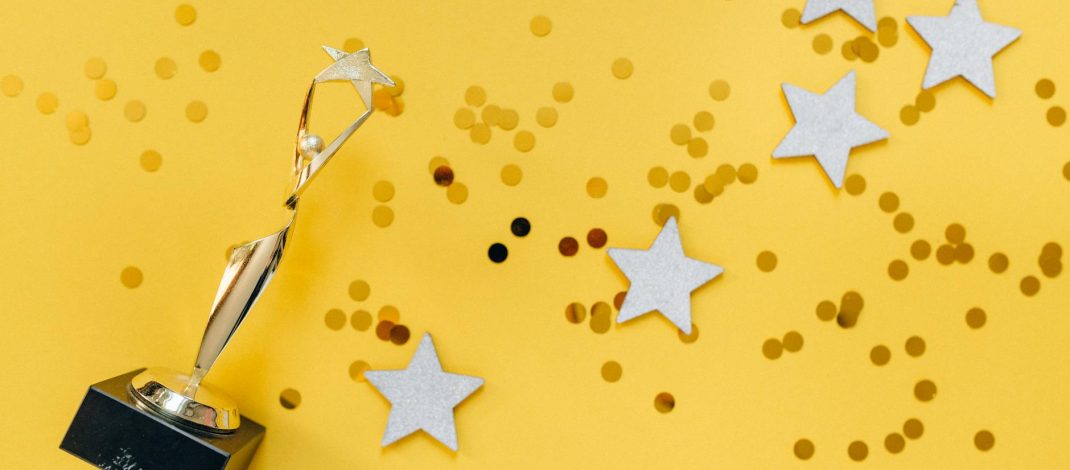 golden statuette and stars on yellow background